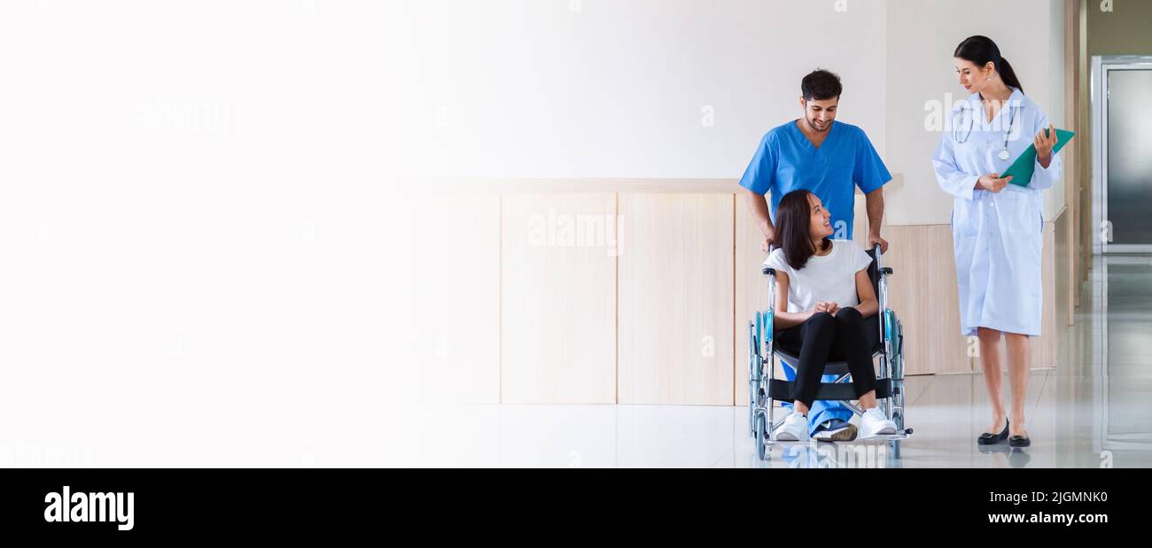 heureuse patiente asiatique souriante assise en fauteuil roulant avec une infirmière masculine parlant au médecin après avoir récupéré un plan de traitement chirurgical à l'hôpital Banque D'Images heureuse patiente asiatique souriante assise en fauteuil roulant avec une infirmière masculine parlant au médecin après avoir récupéré un plan de traitement chirurgical à l'hôpital Banque D'Images