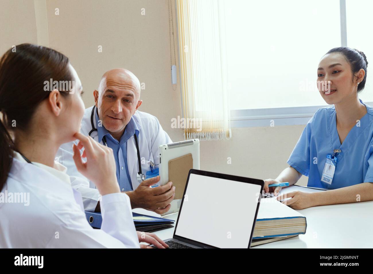 médecin d’équipe, infirmière et médecin de stage parlant et discutant du cas du patient en traitement chirurgical lorsqu’il est assis dans le bureau de la salle de réunion de hos Banque D'Images