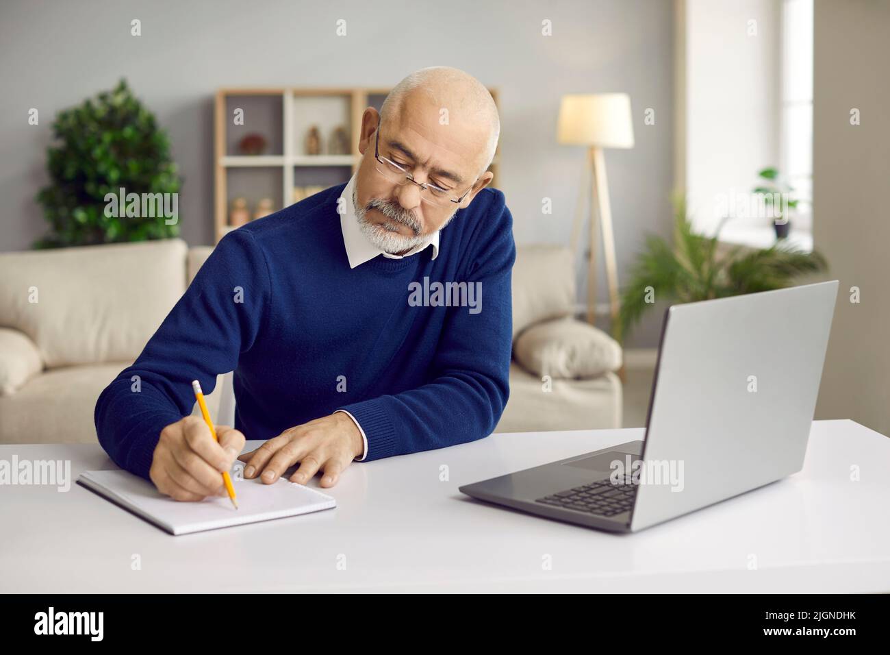 Un homme sérieux et mature travaille sur l'ordinateur pour prendre des notes Banque D'Images
