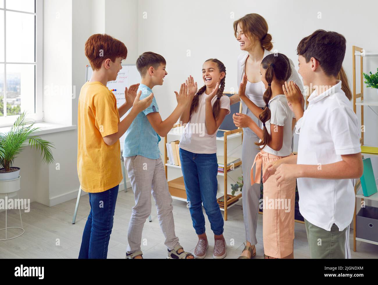 Les écoliers drôles et leur enseignante positive jouent des jeux amusants dans la leçon créative. Banque D'Images