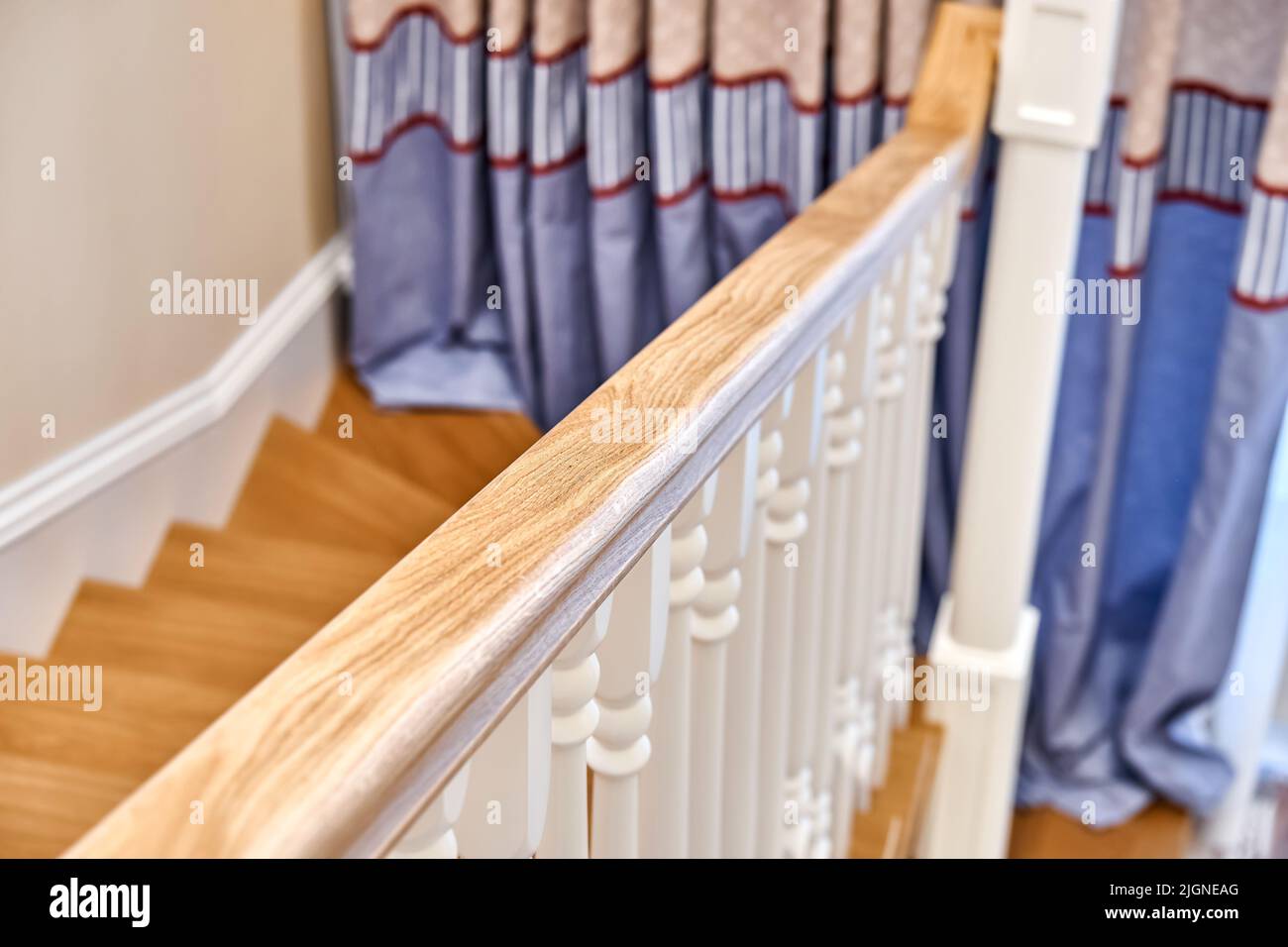 Main courante en bois de chêne massif avec balusters blancs. Escalier en bois de style classique dans une grande chambre lumineuse Banque D'Images