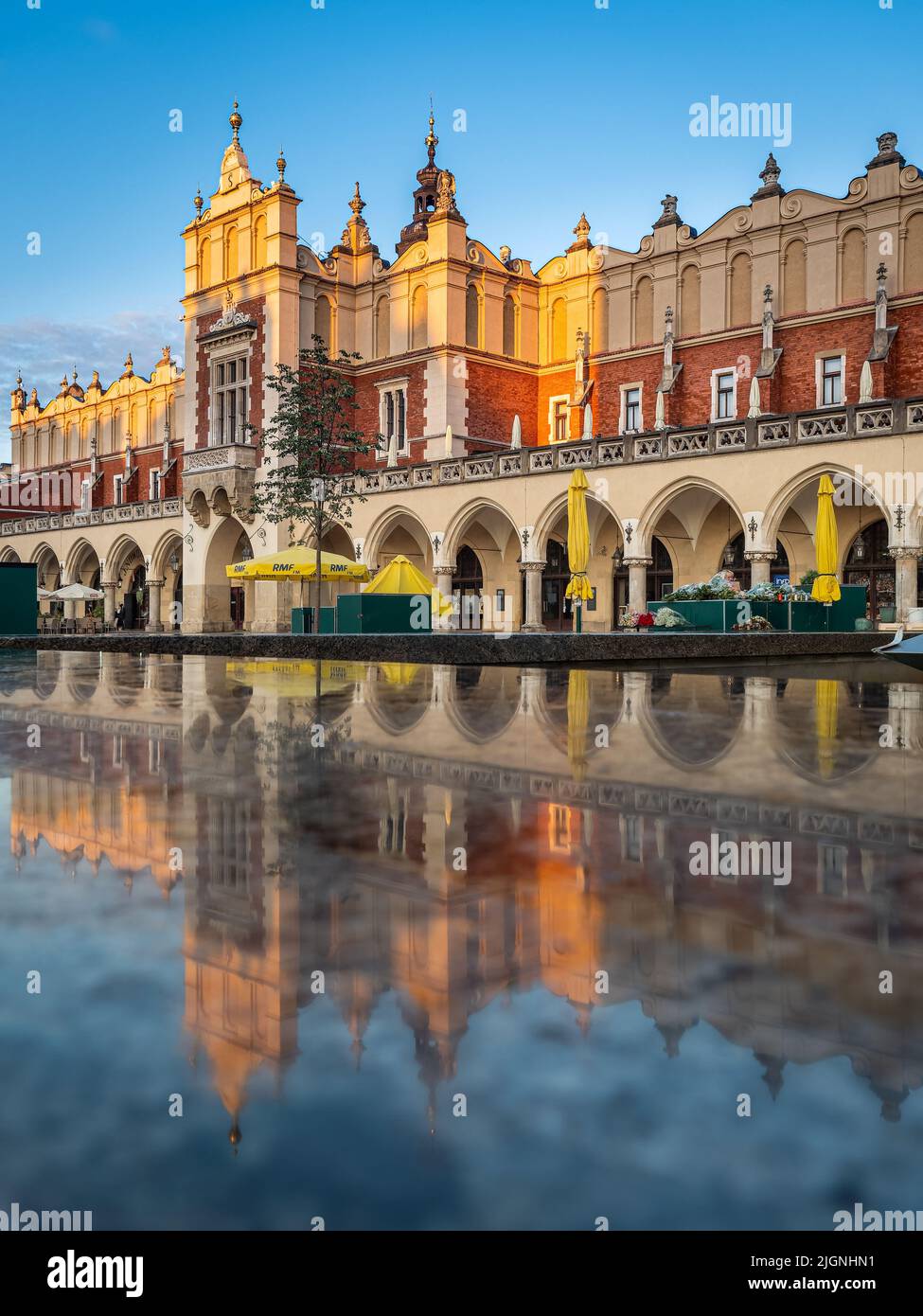 Réflexions du bâtiment en tissu Sukiennice Hall au lever du soleil sur la place principale de Cracovie, en Pologne Banque D'Images