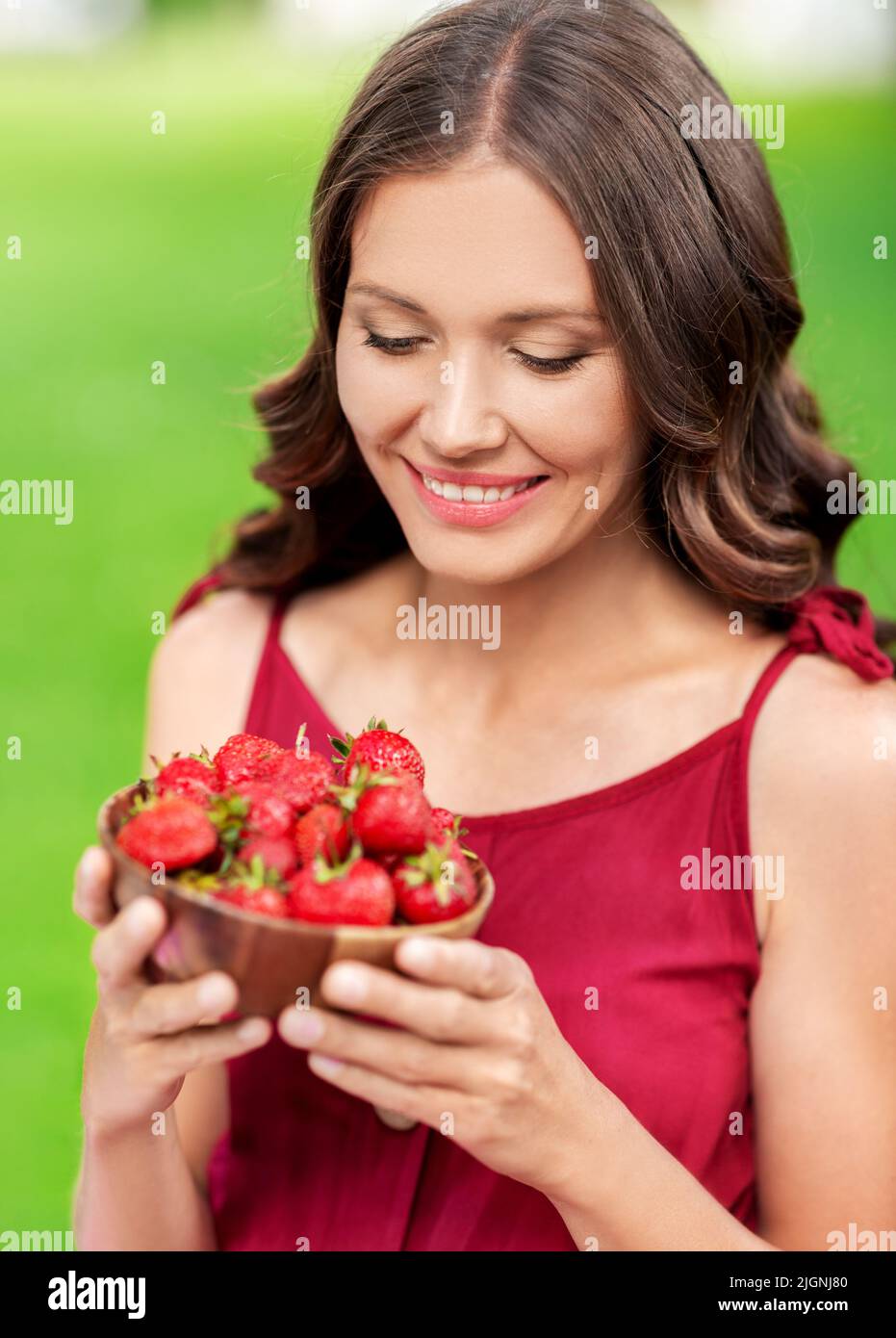 bonne femme mangeant des fraises dans le parc d'été Banque D'Images
