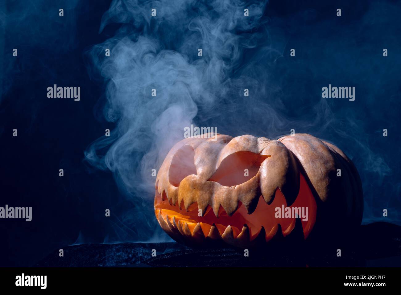 Composition de la citrouille sculptée d'halloween avec fumée sur fond noir Banque D'Images