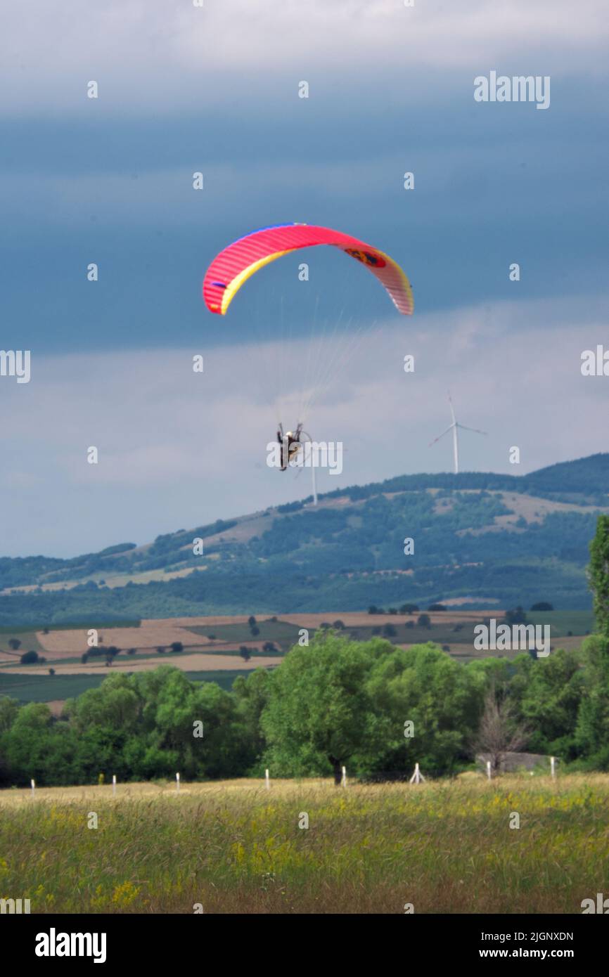 Parachutiste volant près de terre à terre avec des arbres et des collines à l'arrière-plan Banque D'Images