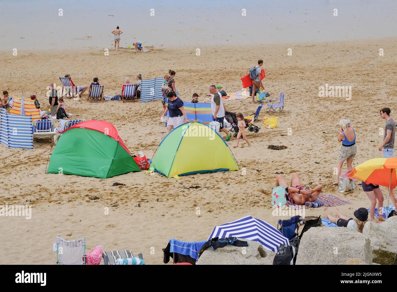 Lors de l'un des jours les plus chauds de l'année dans les vacanciers britanniques sur Fistral Beach ont profité de la chaleur du soleil brumeux et de la brise de mer fraîche sur t Banque D'Images