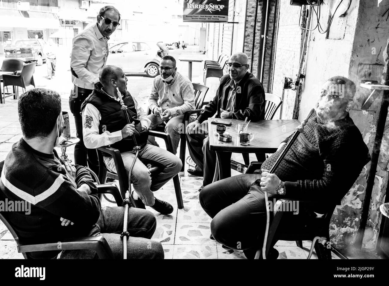 Un groupe d'hommes s'assoient autour D'Une table pour bavarder et fumer les pipes de Shisha, Aqaba, gouvernorat d'Aqaba, Jordanie. Banque D'Images