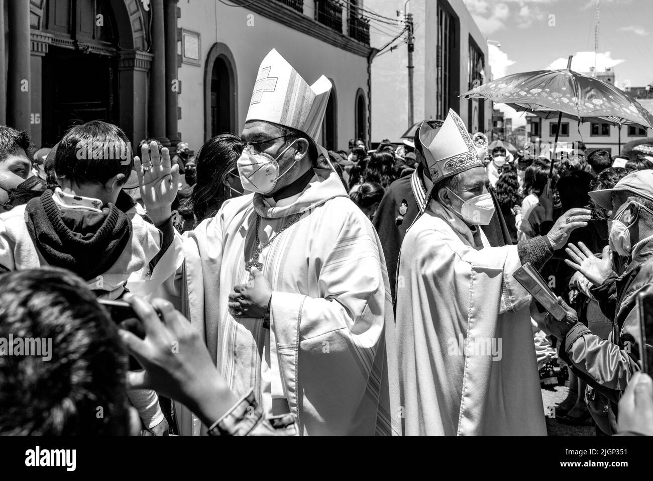 Les prêtres catholiques bénissent les gens dans la foule après une messe en plein air sur la Plaza de Armas, Puno, province de Puno, Pérou. Banque D'Images