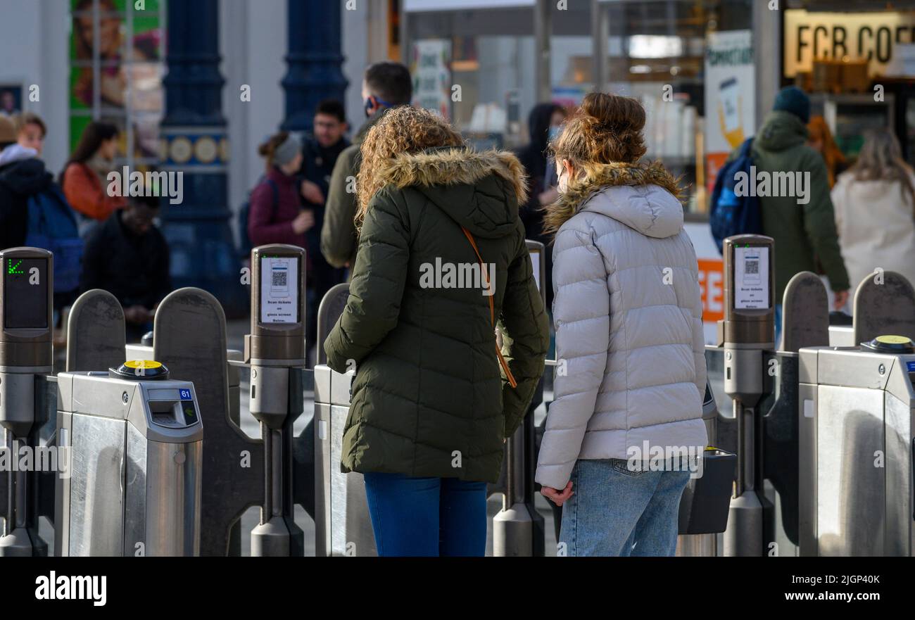 Les passagers franchissant des barrières tarifaires à la gare de Brighton, en Angleterre. Banque D'Images