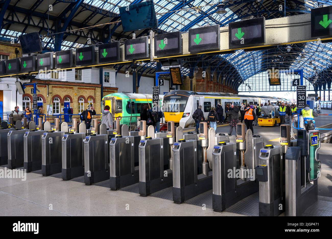 Les passagers franchissant des barrières tarifaires à la gare de Brighton, en Angleterre. Banque D'Images