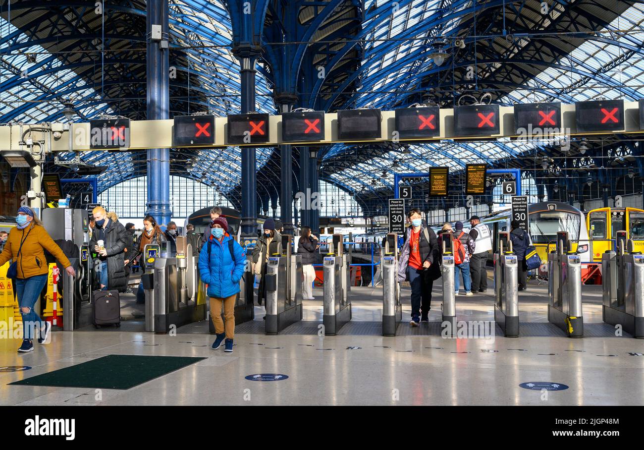 Les passagers franchissant des barrières tarifaires à la gare de Brighton, en Angleterre. Banque D'Images