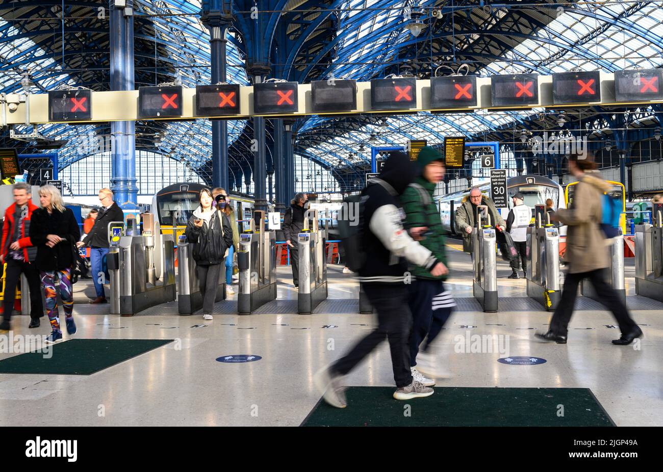 Les passagers franchissant des barrières tarifaires à la gare de Brighton, en Angleterre. Banque D'Images