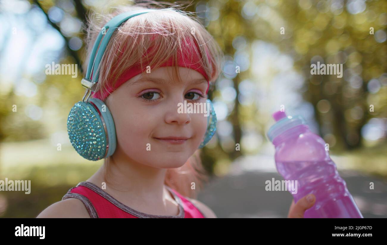 Sport athlétique soif jogger enfant fille boire de l'eau de la bouteille après l'entraînement s'exerçant. Entraînement cardio dans le parc le matin. Le coureur pour tout-petits apprécie un mode de vie sain. Activités enfants actives Banque D'Images