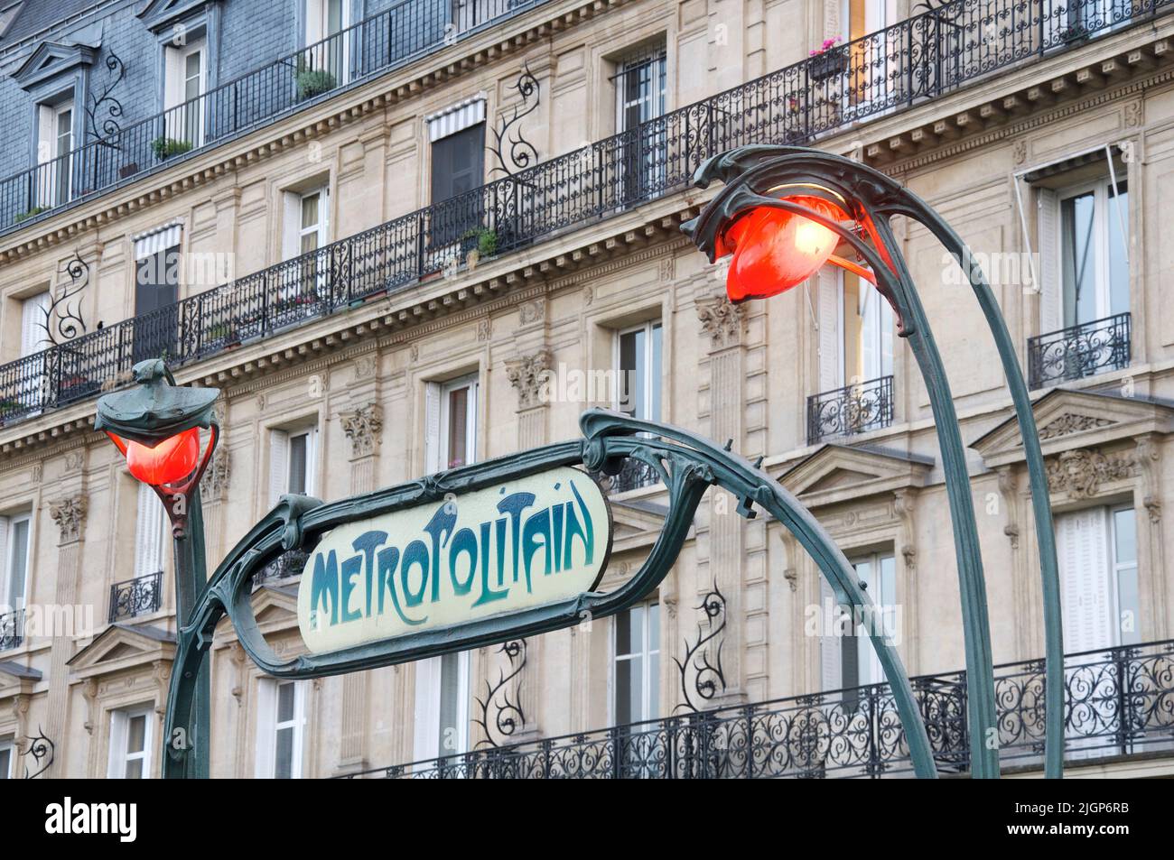 Emblématique panneau de métro Art Nouveau parisien conçu par Hector Guimard, à l'entrée de la station Europe. Avec des lampes sinueuses décoratives orange éclatant. Banque D'Images