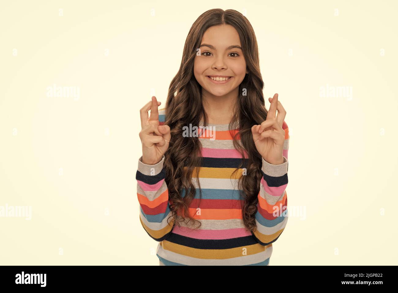 J'espère que mon souhait va se réaliser. Sourire heureux de l'enfant en gardant les doigts croisés. Bonne chance. Banque D'Images