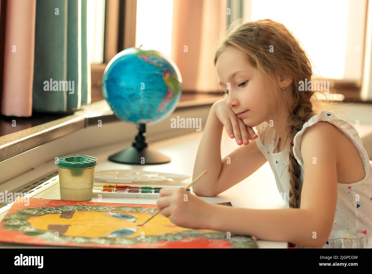 Portrait de fille enfant est la peinture avec des couleurs gouache et image de pinceau tout en étant assis à la table sur le fond de la pièce de maison. Banque D'Images