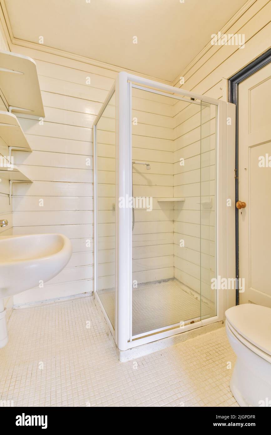 Lavabos avec miroirs et toilettes propres situés près de la boîte de douche avec porte en verre dans la salle de bains moderne avec murs carrelés blancs Banque D'Images