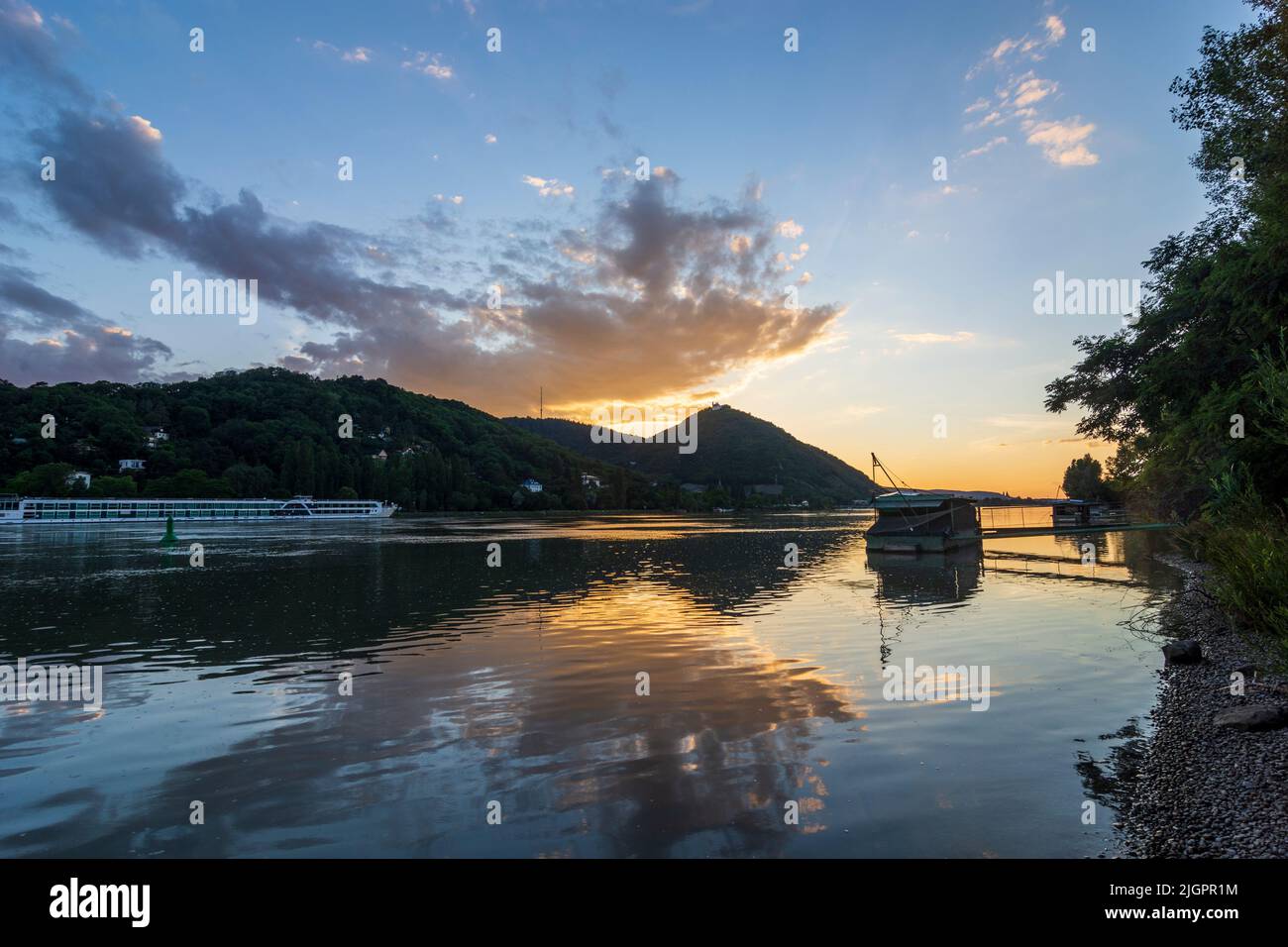 Wien, Vienne: Coucher de soleil sur le Donau (Danube), vue sur la montagne Kahlenberg (à gauche) et Leopoldsberg (avec église), bateau Daubel avec filet de pêche, Banque D'Images