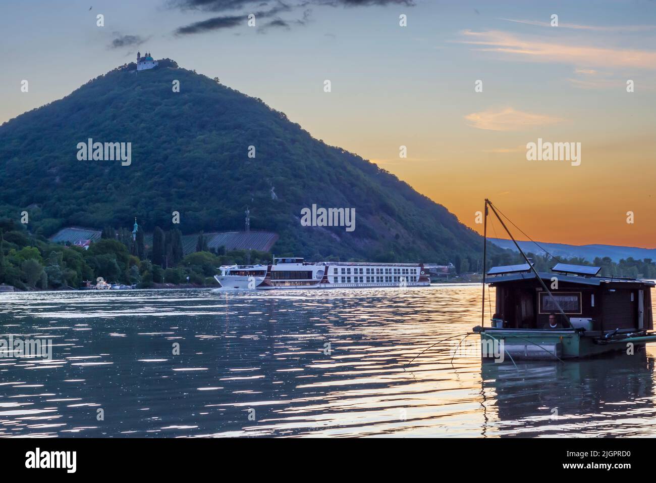 Wien, Vienne: Coucher de soleil sur le Donau (Danube), vue sur la montagne Leopoldsberg (avec église), bateau Daubel avec filet de pêche, bateau de croisière en 19. Dö Banque D'Images