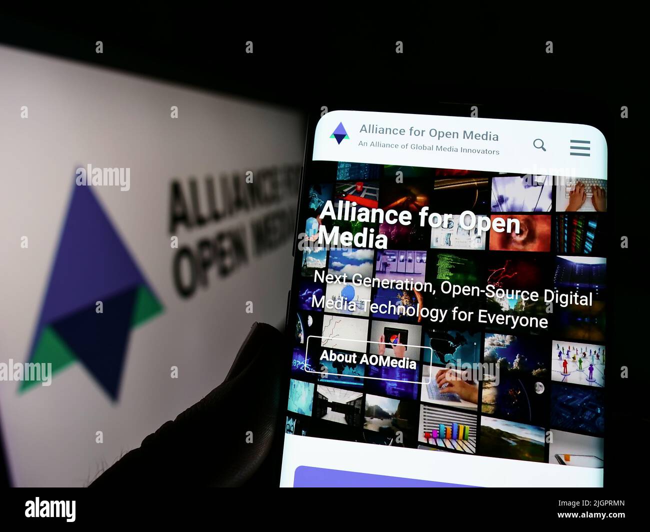 Personne tenant un téléphone portable avec la page web du consortium Alliance for Open Media (AOMedia) à l'écran avec logo. Concentrez-vous sur le centre de l'écran du téléphone. Banque D'Images