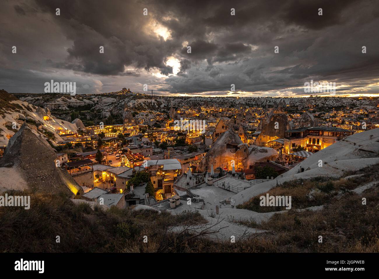 ville ​​of göreme en turquie au coucher du soleil avec des lumières allumées et des nuages sombres. Banque D'Images