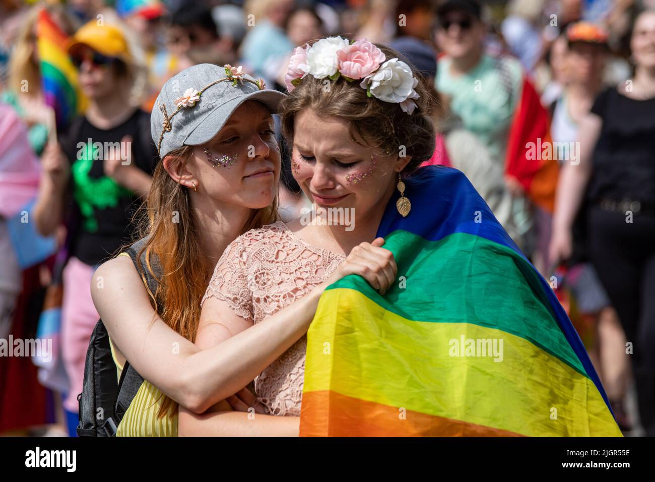 Une femme qui pleure avec un drapeau de fierté étant réconfortée par un ami ou un partenaire à la parade de la fierté d'Helsinki 2022 à Helsinki, en Finlande Banque D'Images
