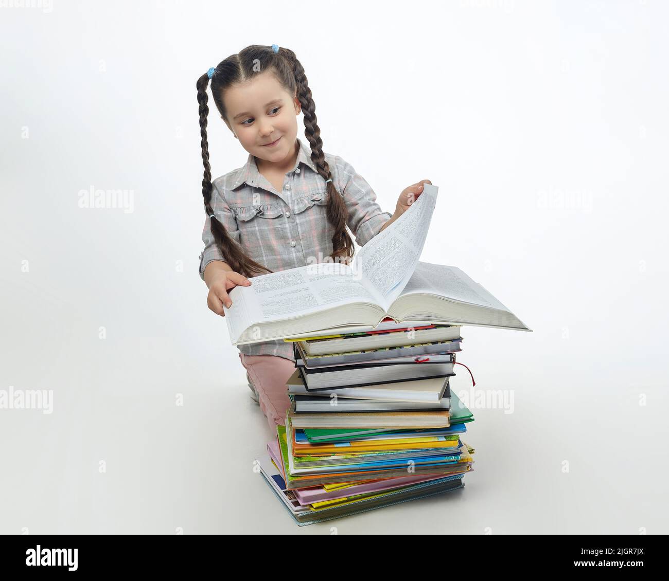 charmante petite fille tourne la page d'un grand livre. Banque D'Images