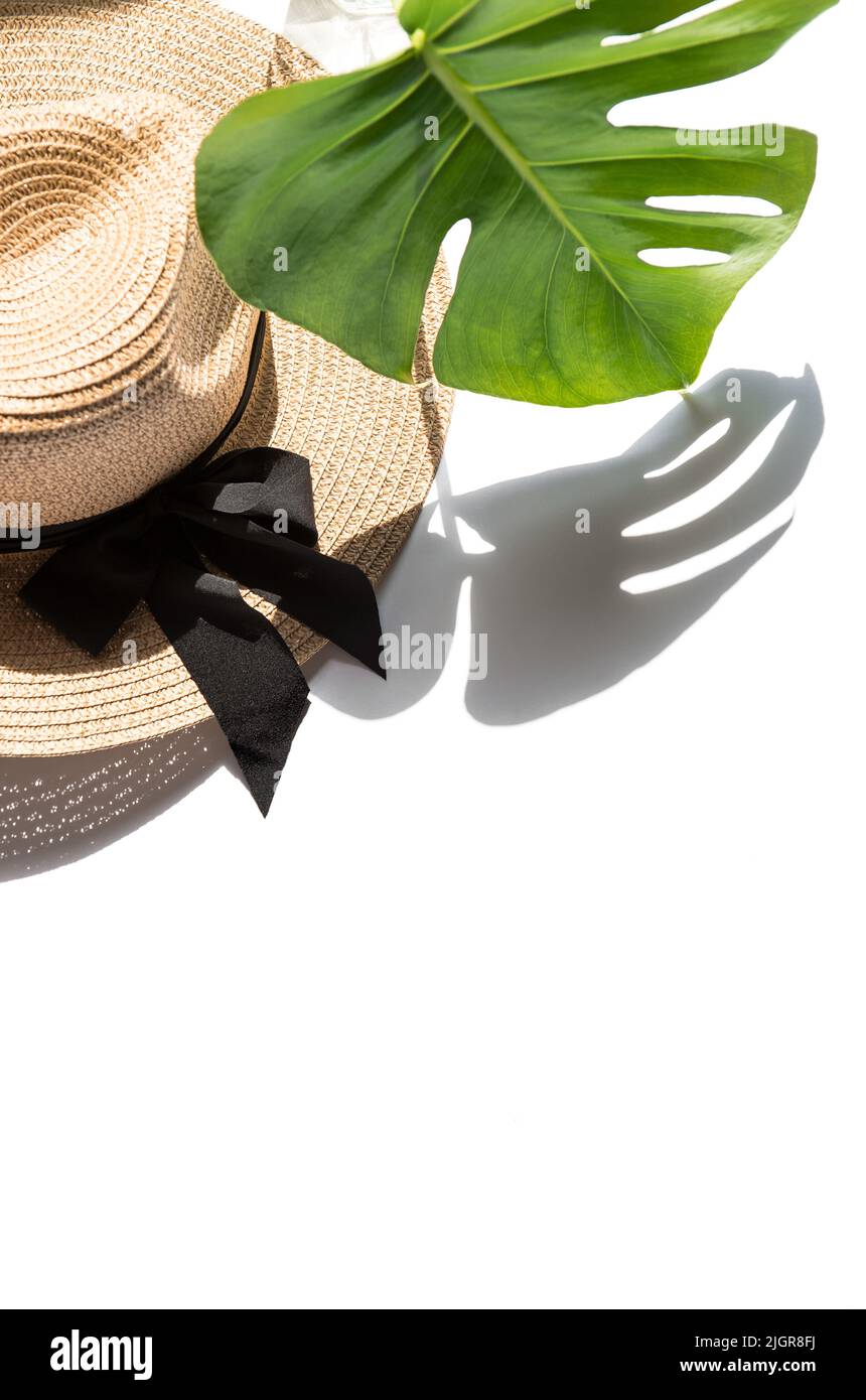 Modèle de pose à plat d'été. Chapeau de paille et ombre de feuilles de monstère Banque D'Images