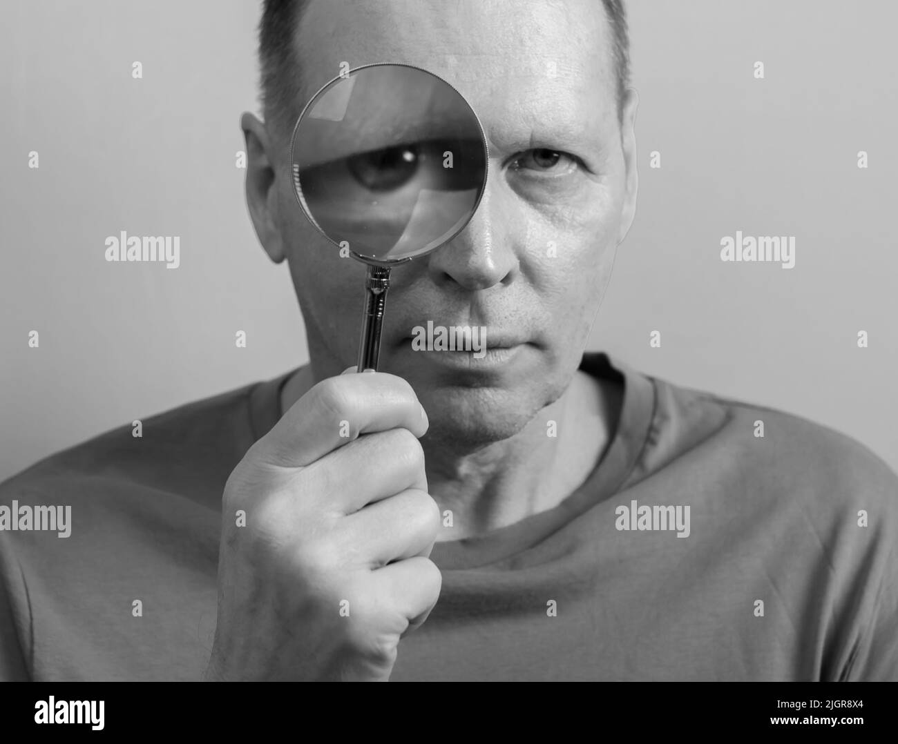 Personne regardant à travers loupe verre avec curiosité, suspicion. Banque D'Images