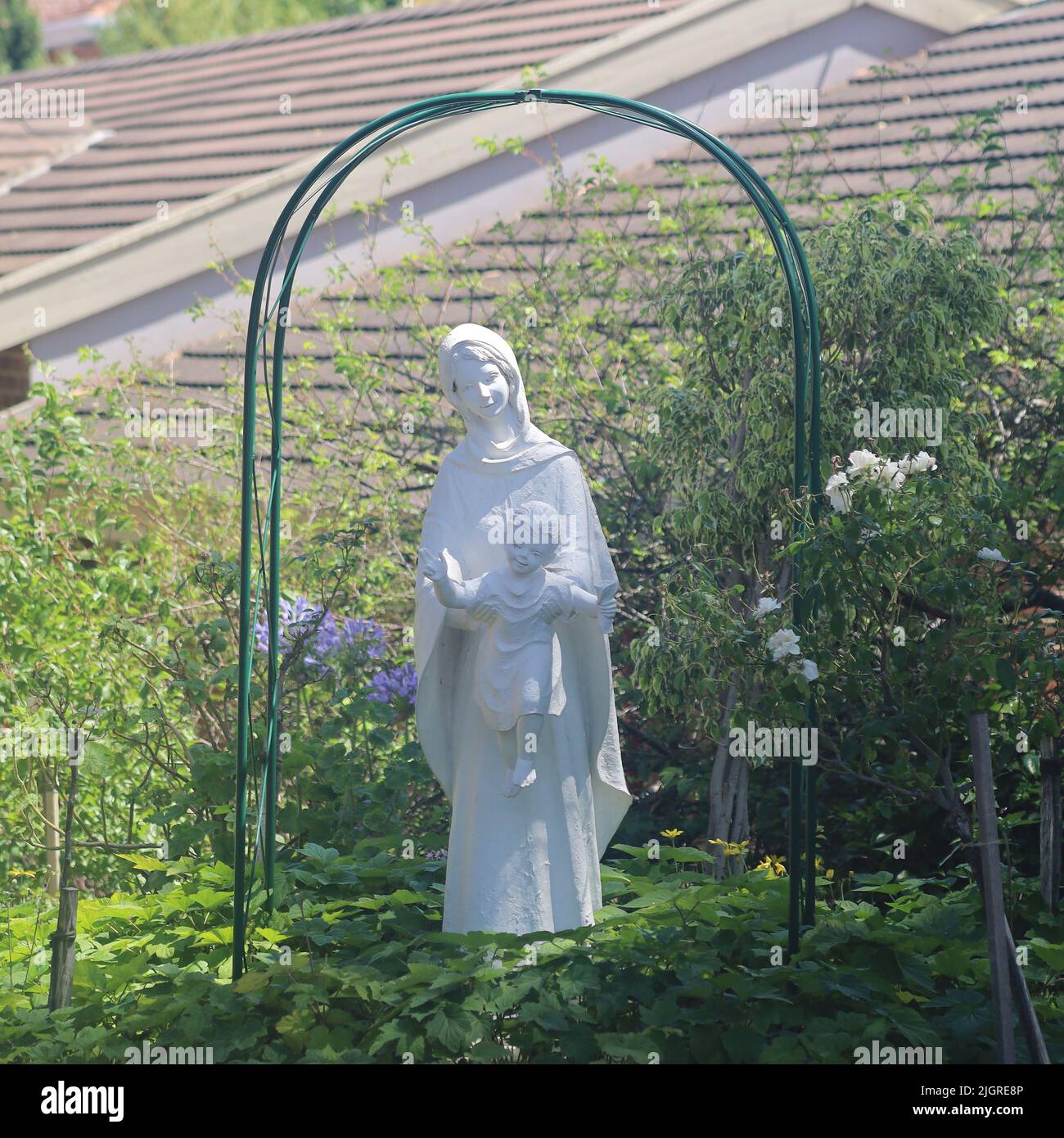 Une statue de la Vierge Marie tenant bébé Jésus dans un jardin Banque D'Images