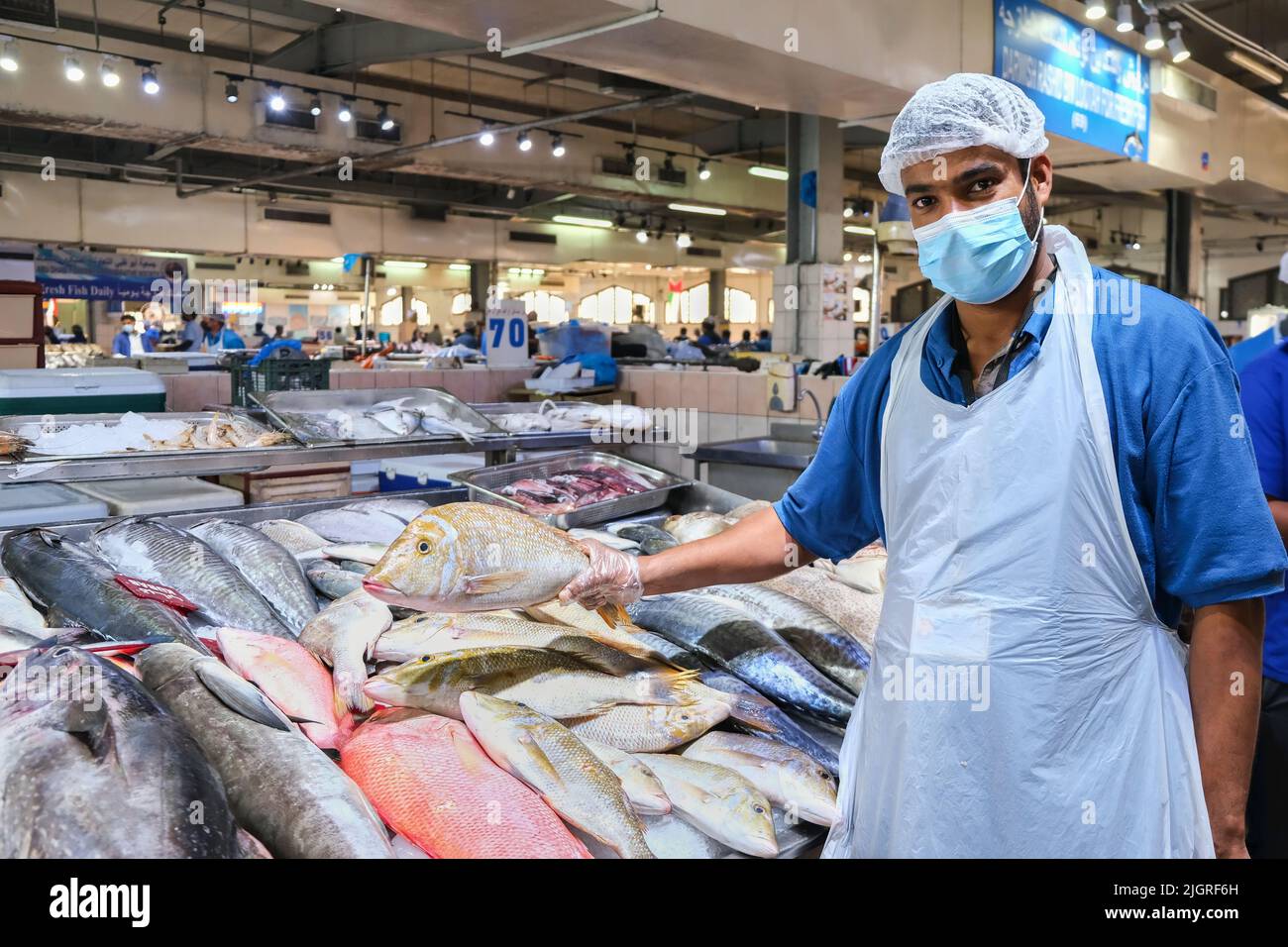 Portrait de jeune adulte beau moyen-oriental poissonnier portant le masque, regardant l'appareil-photo, la vente de poisson frais sur le marché traditionnel de poissons de fruits de mer. EAU Banque D'Images