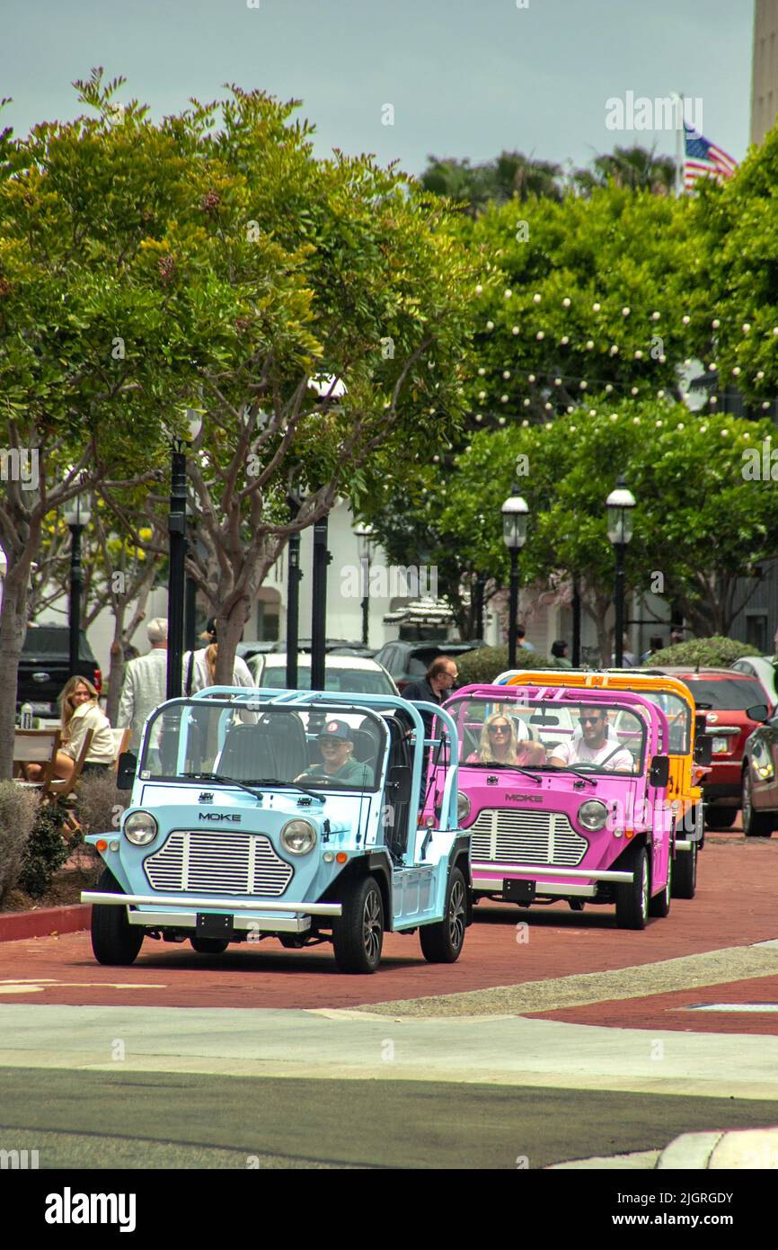 Une procession de voitures électriques miniatures Moke colorées tour Lido Marina Village sur Newport Beach, CA's Balboa Peninsular. Banque D'Images