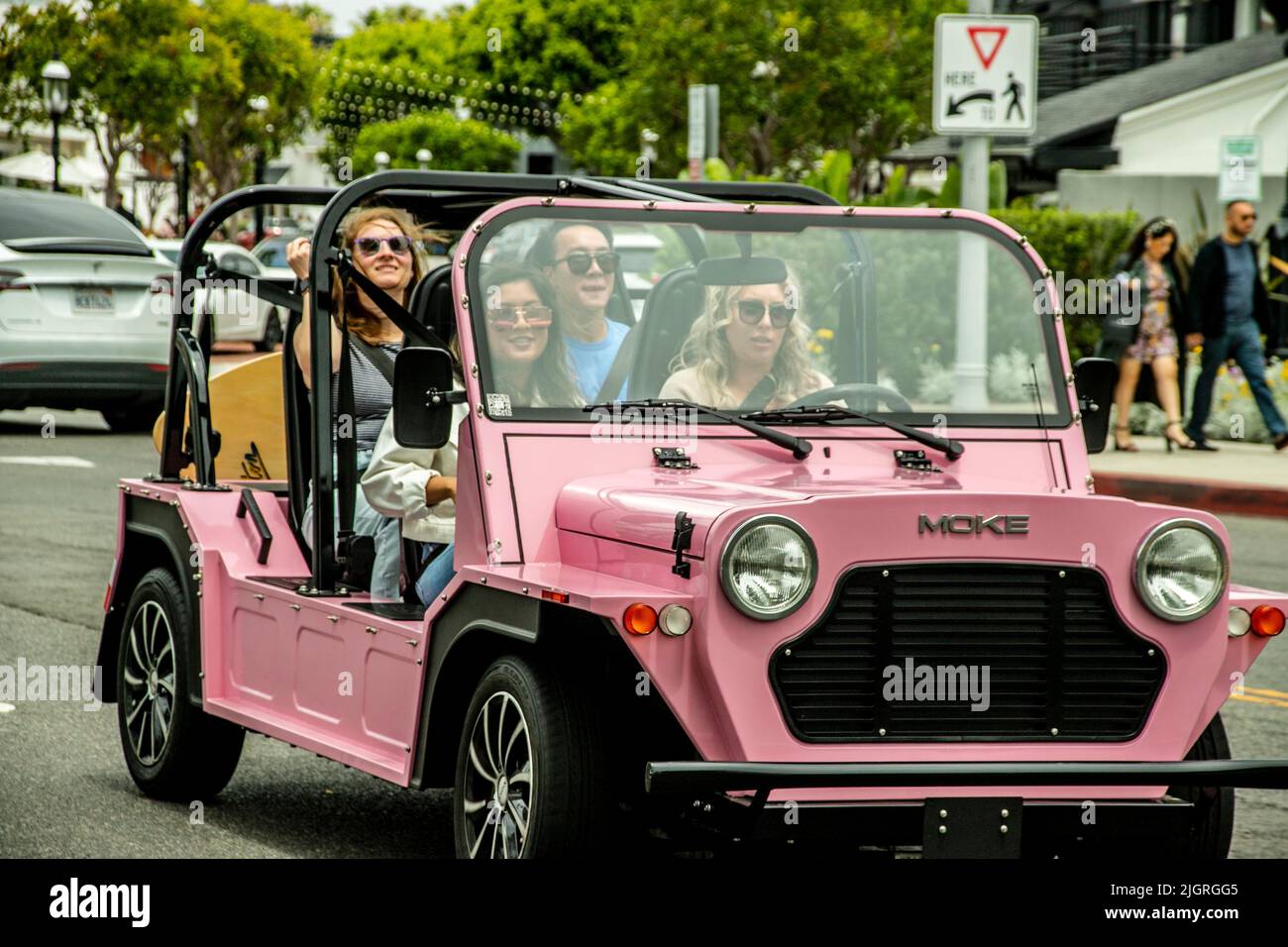 Une procession de voitures électriques miniatures Moke colorées tour Lido Marina Village sur Newport Beach, CA's Balboa Peninsular. Banque D'Images