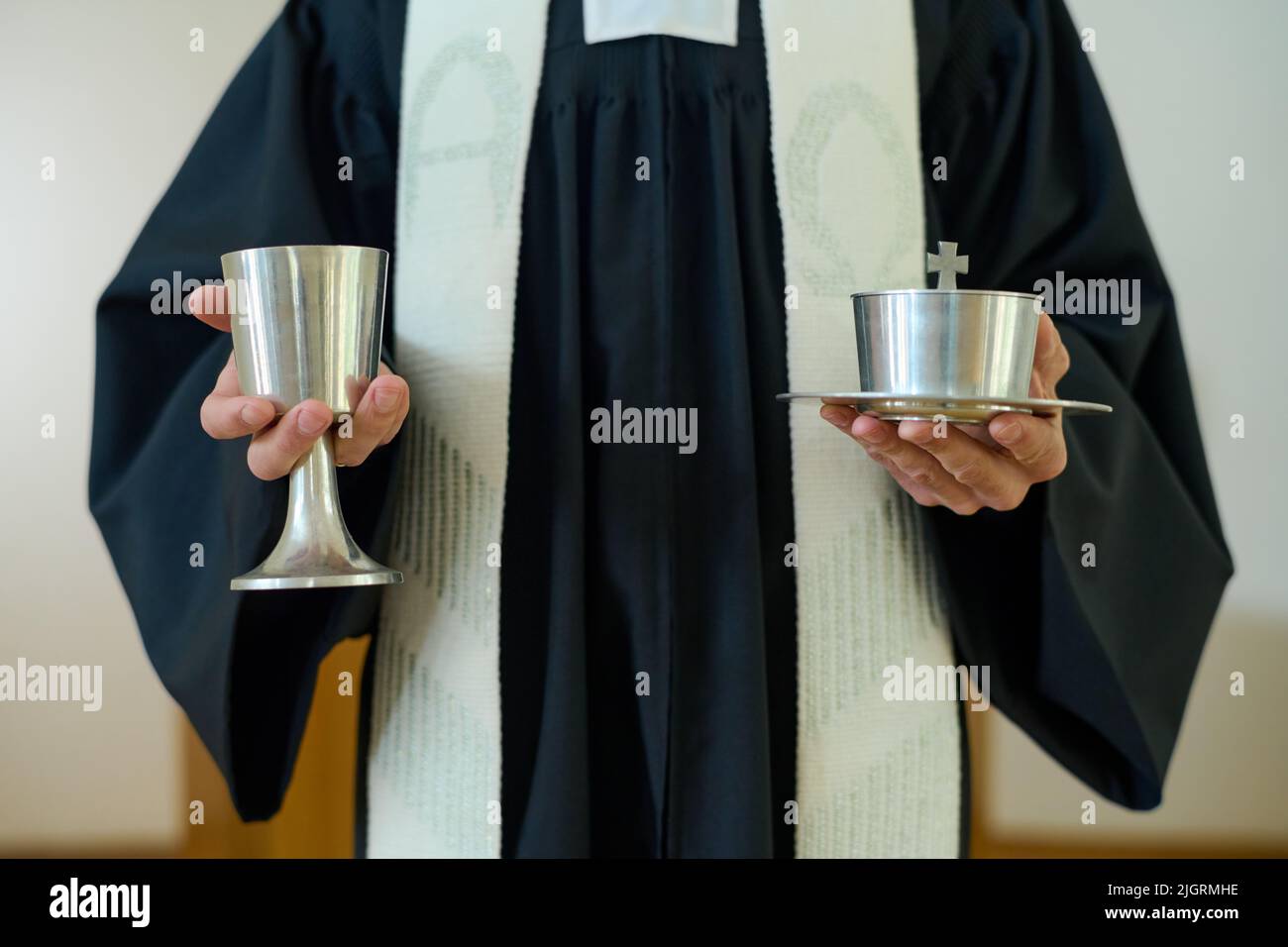 Mains du prêtre catholique en cassock tenant deux tasses de vin et pain sans levain pour la communion des paroissiens de l'église Banque D'Images