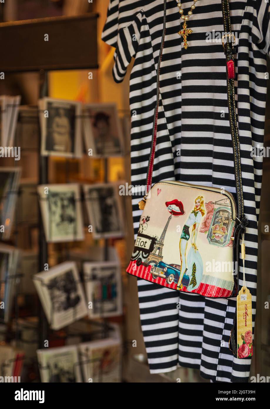 Robe rayée et sac à main sur les cintres dans un magasin de rue, gros plan. Collection de vêtements en vacances pour l'été. Photo de rue, photo de voyage, personne, selec Banque D'Images