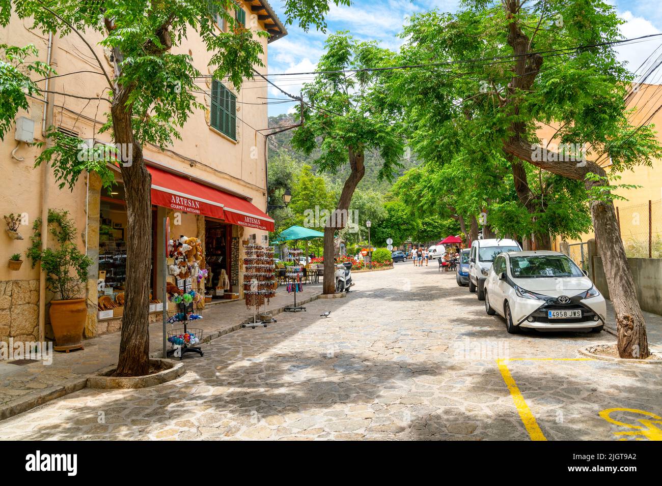 Une des nombreuses rues pittoresques bordées d'arbres de boutiques et de cafés dans le village perché de Valldemossa, en Espagne, sur l'île de Majorque, en Espagne. Banque D'Images
