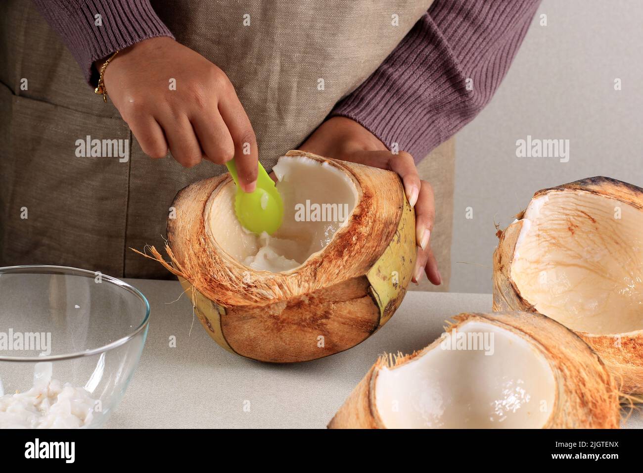 Viande de noix de coco déchiquetée à la main de femme, transformation dans la cuisine Banque D'Images