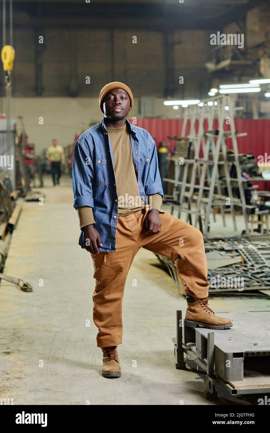 Portrait d un jeune homme africain en vetements de travail regardant la camera debout dans l atelier de l usine Photo Stock Alamy