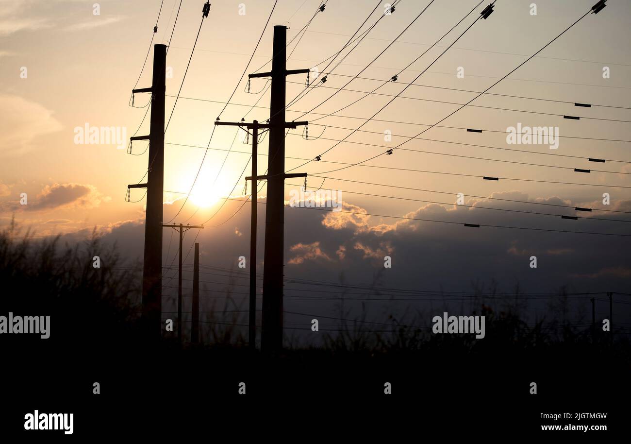 (220713) -- HOUSTON, 13 juillet 2022 (Xinhua) -- le soleil se couche derrière les lignes de transmission de puissance au Texas, aux États-Unis sur 11 juillet 2022. Le Electric Reliability Council of Texas (ERCOT) a demandé lundi aux résidents et aux entreprises de réduire leur consommation d'énergie car l'indice thermique dépassait 100 degrés Fahrenheit dans environ la moitié de l'État du centre-sud des États-Unis. Cette vague de chaleur a commencé il y a plus d'une semaine et continue de se renforcer, défiant le réseau électrique de l'État. Les températures quasi-records dans la plupart des États du Texas ont forcé divers événements en plein air à être retardés ou annulés en raison de problèmes de sécurité. (Tél Banque D'Images