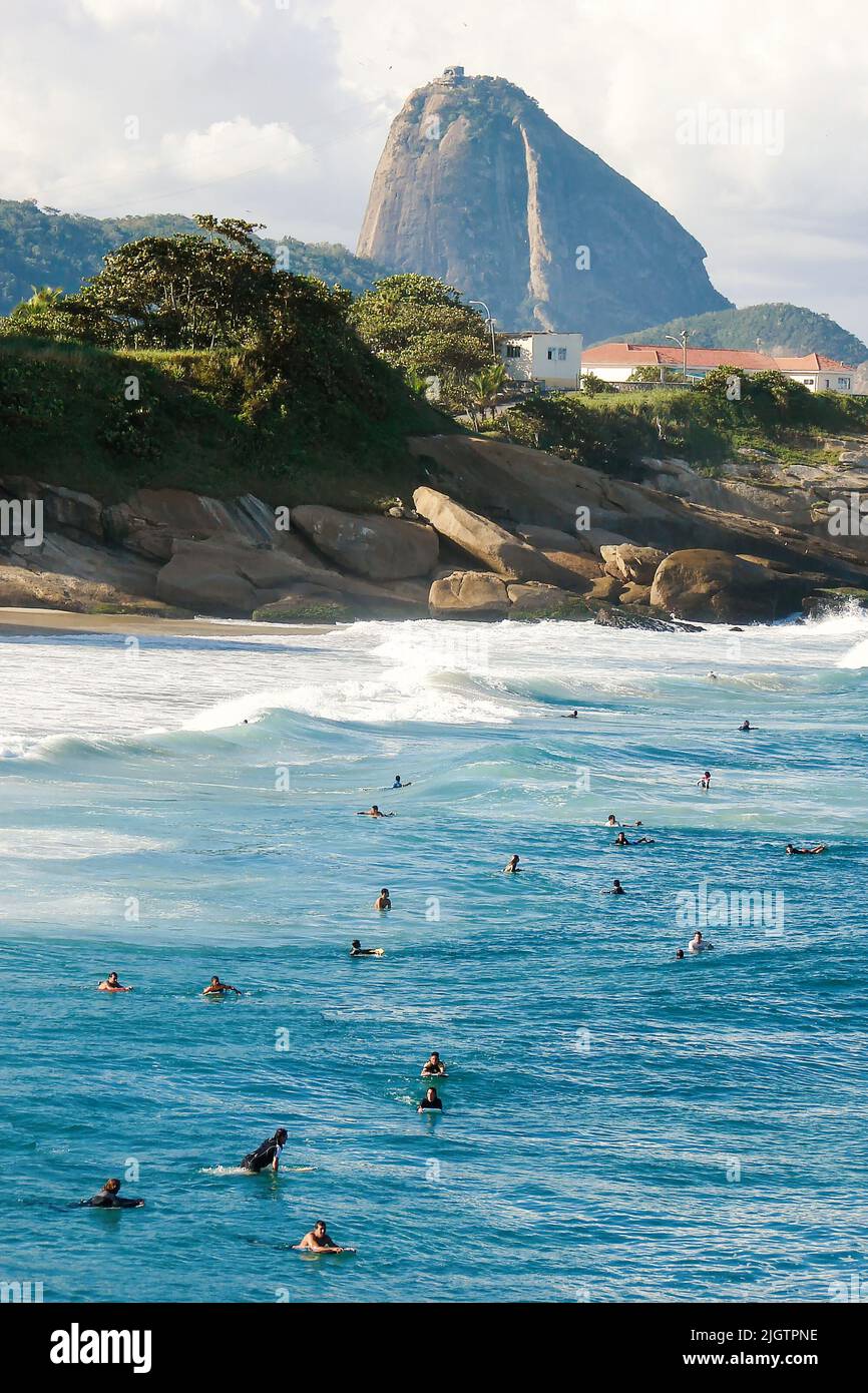 Surfeurs attrapant une vague sur la plage de Copacabana à Rio de Janeiroin le fond de la montagne Sugarloaf Banque D'Images