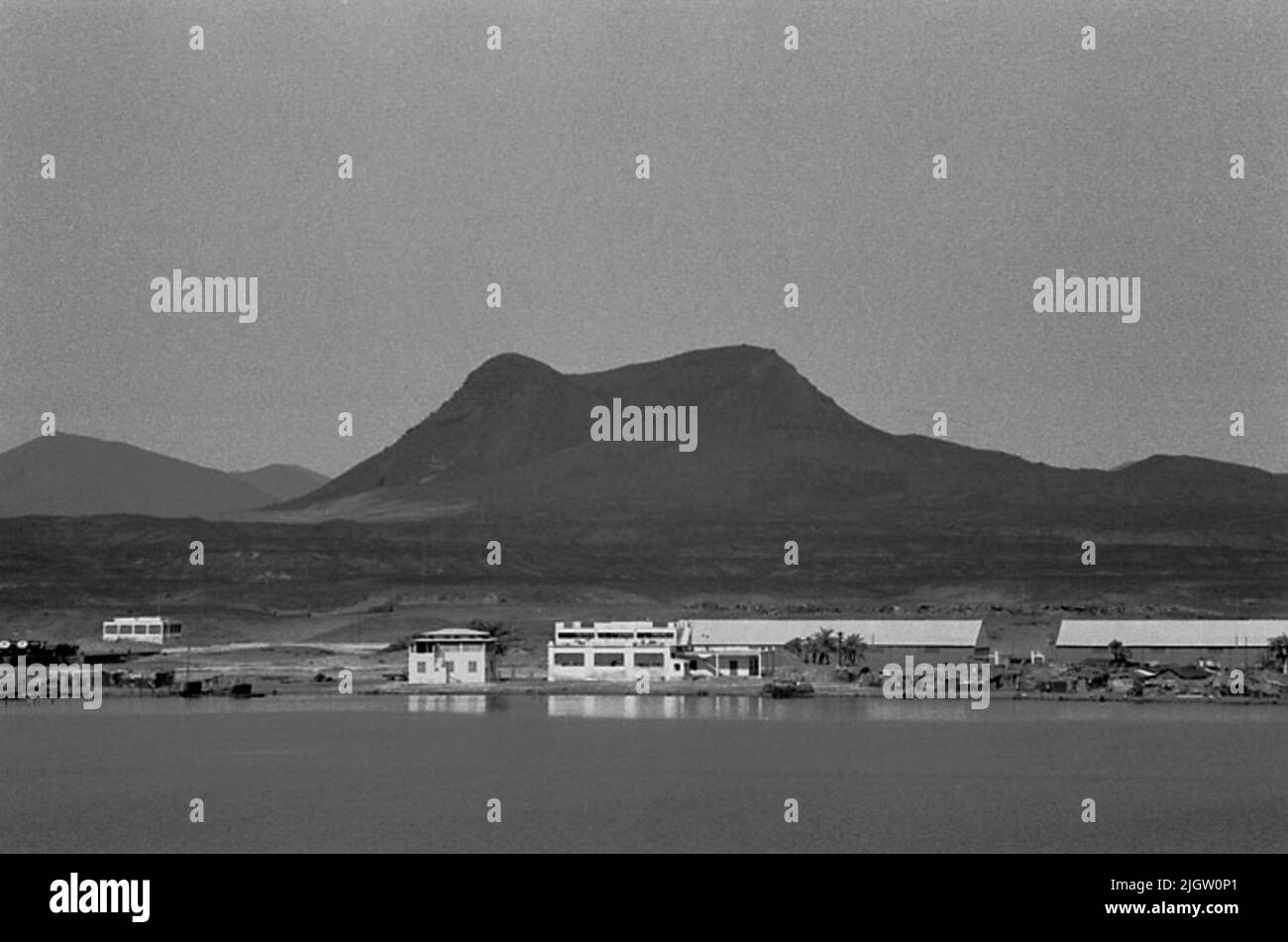 La photo a été prise vers le 1961-08-30. Quelques maisons et magazines sont situés sur la plage d'une baie de mer. En arrière-plan, quelques montagnes Levez-vous. African travel35 images en série. Banque D'Images