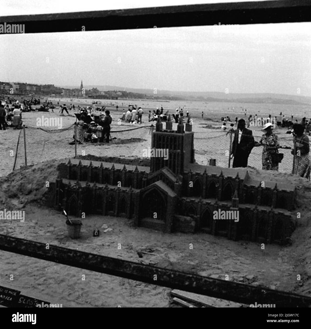 Un château de sable est construit sur une plage de sable. Plusieurs femmes et hommes marchent sur la plage et regardent les œuvres d'art. Imaginez une photo de France (?), de Belgique (?). Banque D'Images