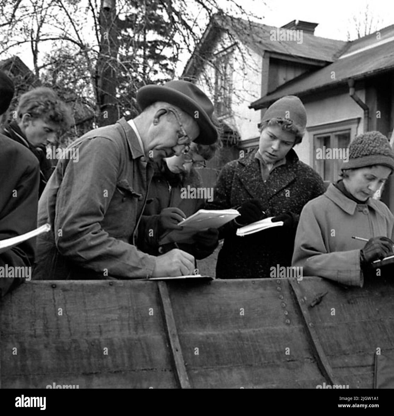 Un certain nombre d'hommes et de femmes discutent à un bateau qui est ouvert dans un jardin. Pour les notes. En arrière-plan se trouve un bâtiment résidentiel. Banque D'Images