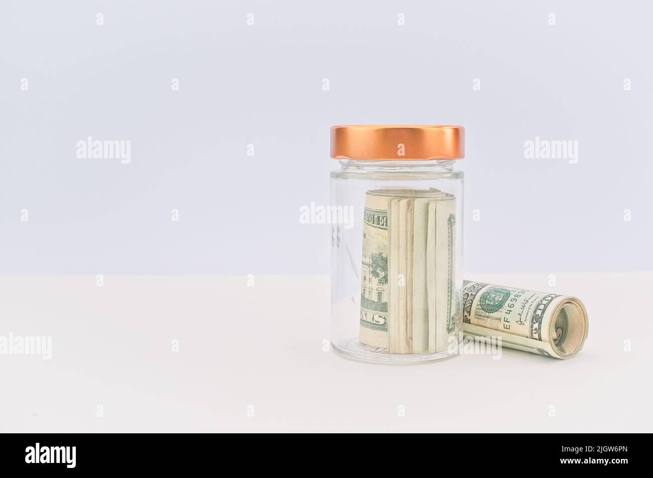 rouleau d'argent dans un pot en verre sur un bureau blanc lumineux avec espace de copie - concept économique Banque D'Images