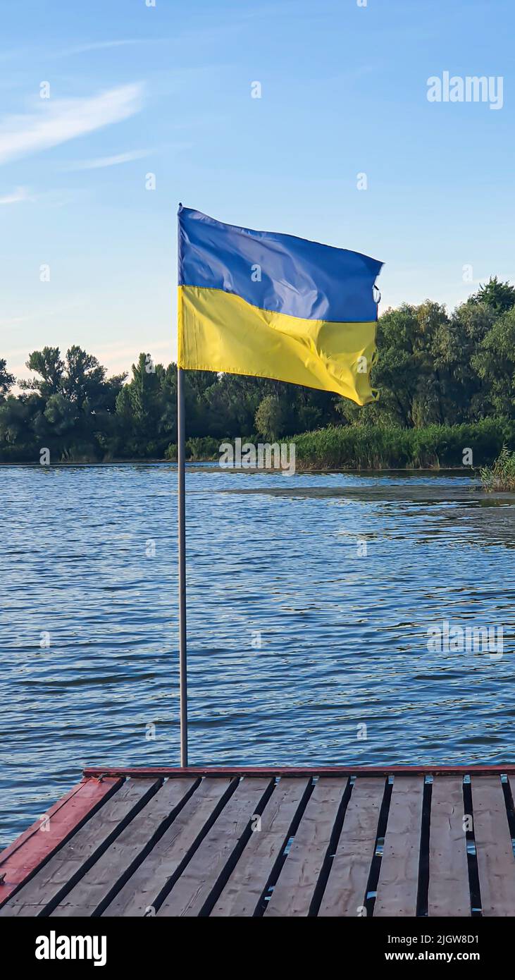 Les drapeaux ukrainiens flottent sur la jetée de la rivière. Jour ensoleillé d'été. Symboles de l'Ukraine. La rive du réservoir. Banque D'Images