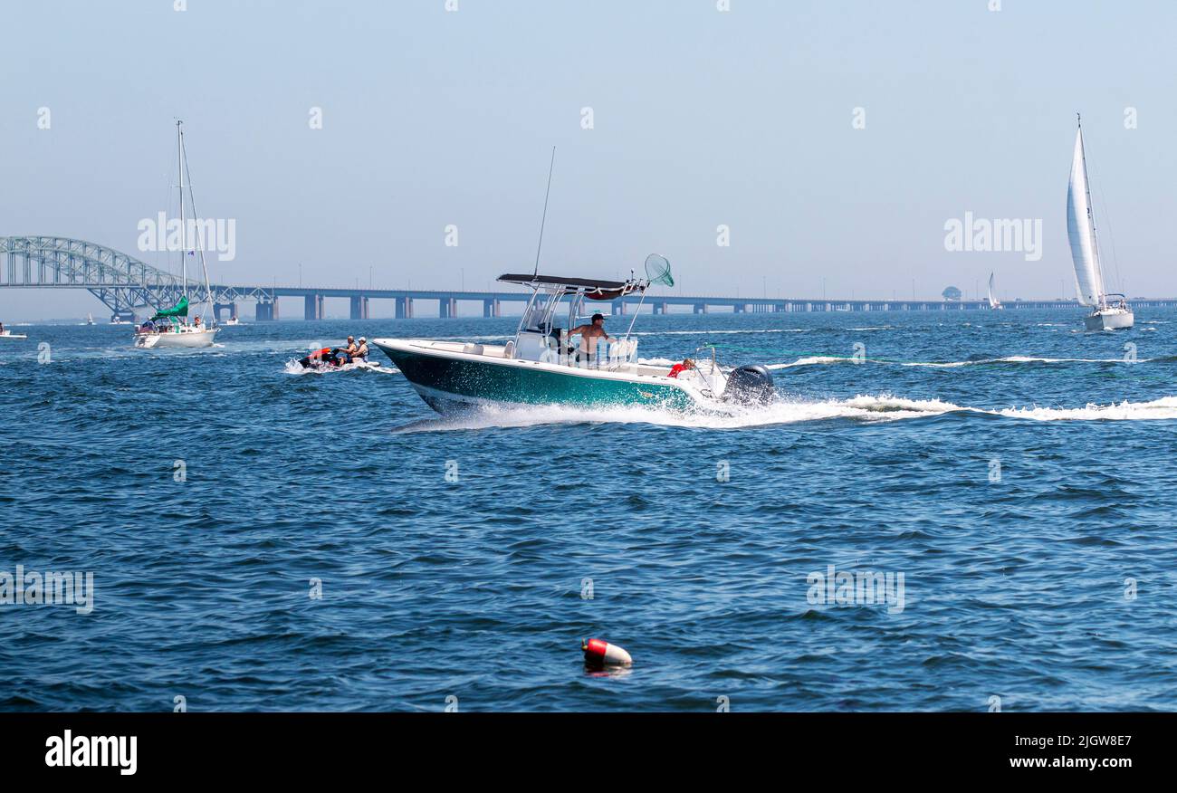 Babylone, New York, Etats-Unis - 25 juin 2022 : les bateaux à moteur, les voiliers et les waverunners se déplacent rapidement dans la grande baie sud avec le pont en vue. Banque D'Images