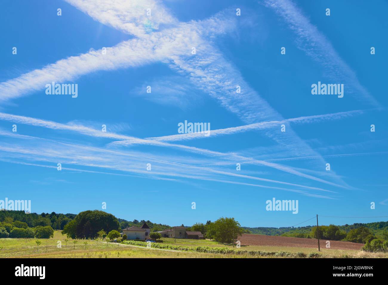 13 juillet 2022. Lot et Garonne, Sud-Ouest de la France. Les pistes de vapeur d'avion traversent un ciel bleu clair au milieu de la sécheresse et des restrictions d'utilisation de l'eau pour l'agriculture. Banque D'Images