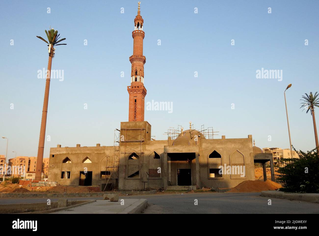 Une nouvelle mosquée est en construction contre le ciel bleu ensoleillé avec le minaret de la mosquée et les dômes entourés d'un échafaudage en bois et de fenêtres sous const Banque D'Images