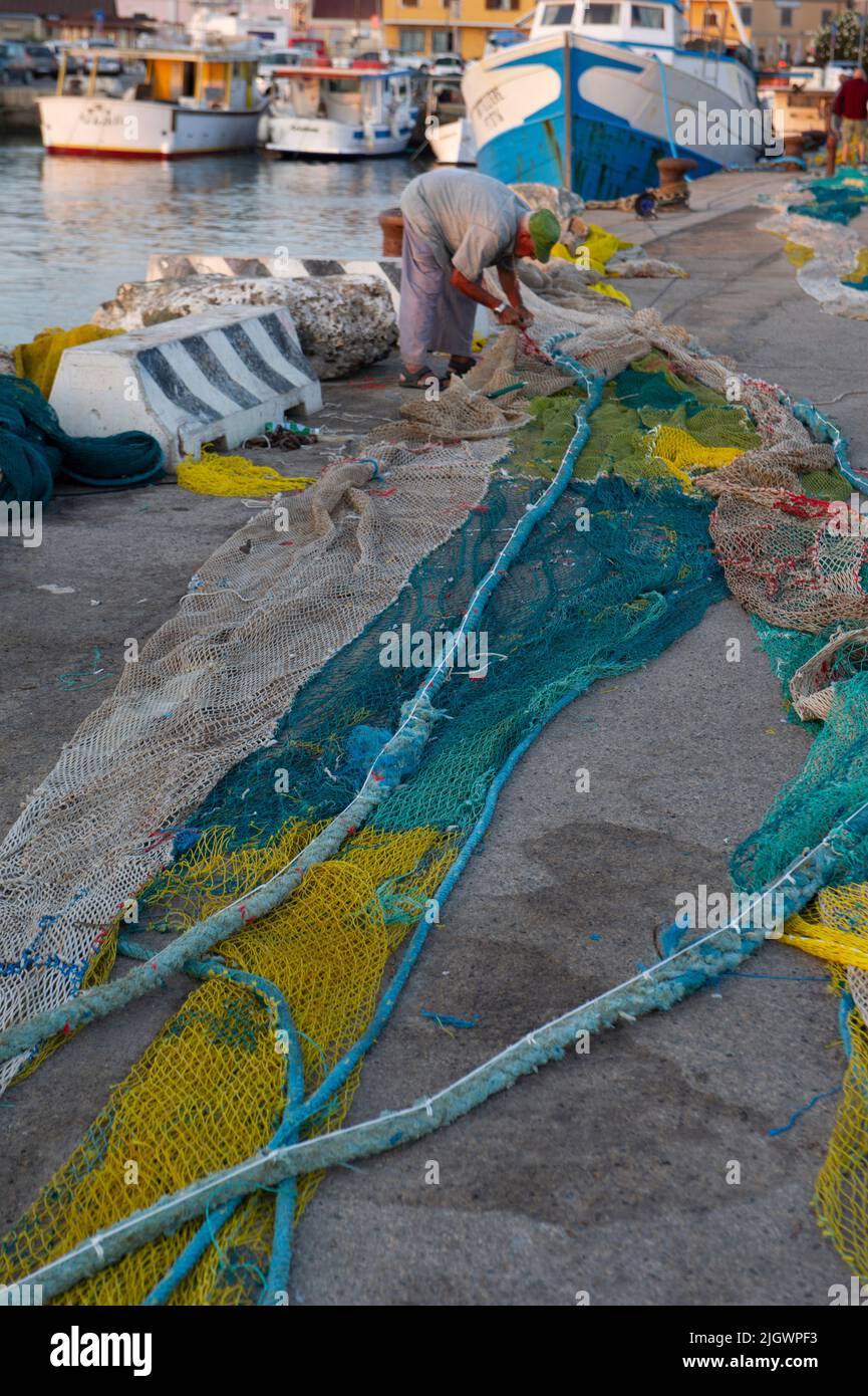 Europa, Italia, Sardegna, Porto Torres, Pescatore ripara le reti rotte Banque D'Images