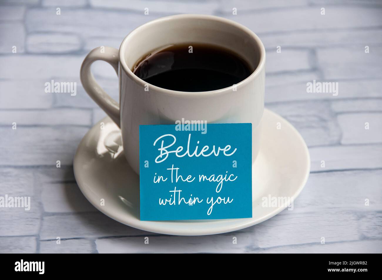 Citations motivantes et inspirantes sur un bloc-notes bleu avec une tasse de café - croyez en la magie en vous. Banque D'Images